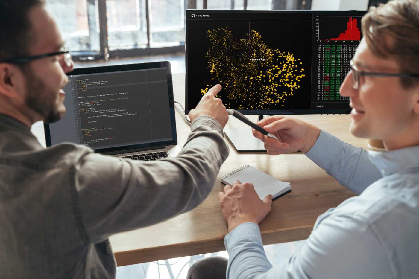 Closeup of two machine learning specialists descanting about new project in office in front of pc, analyzing data. Selective focus on computer screen